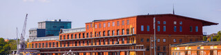Blick auf die Lübecker Altstadt am Abend mit orange-gelbem Himmel, mit der Trave und Schiffen im Vordergrund